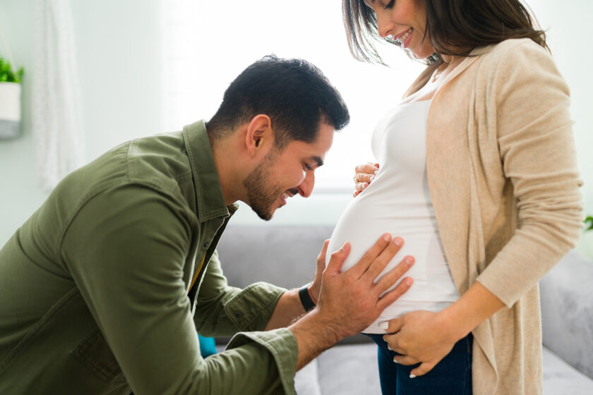 Photo of a husband holding his wife's pregnant belly used as a feature image for an article about how to increase fertility.