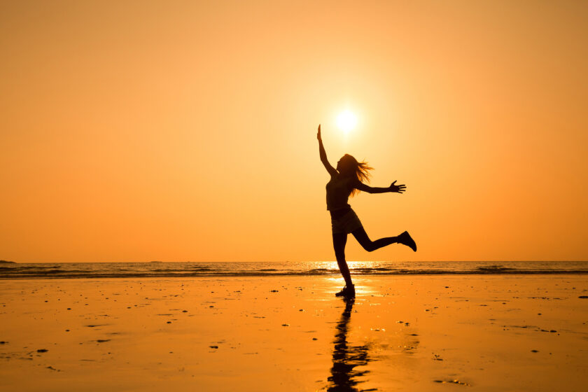 Silhouette of a young woman jumping, celebrating a healthy, happy life.