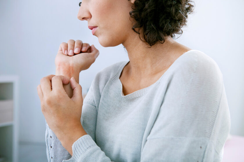 Woman itching skin due to psoriasis.