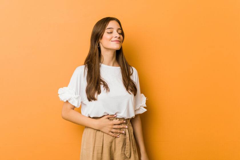 Young woman with hand on abdomen, smiling.